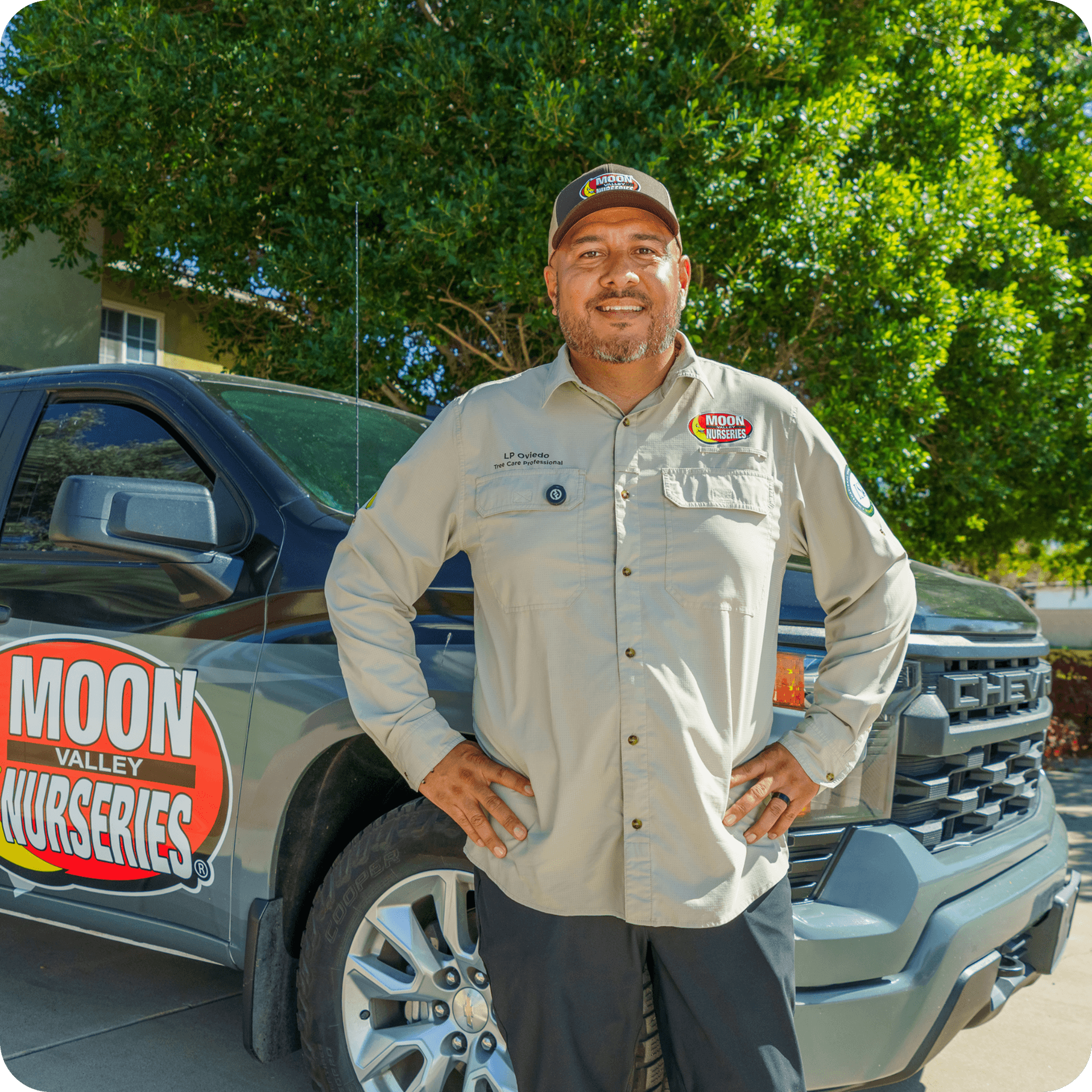 Photo of a Moon Valley Nurseries® expert standing in front of a Tree Care truck at the home of a client.